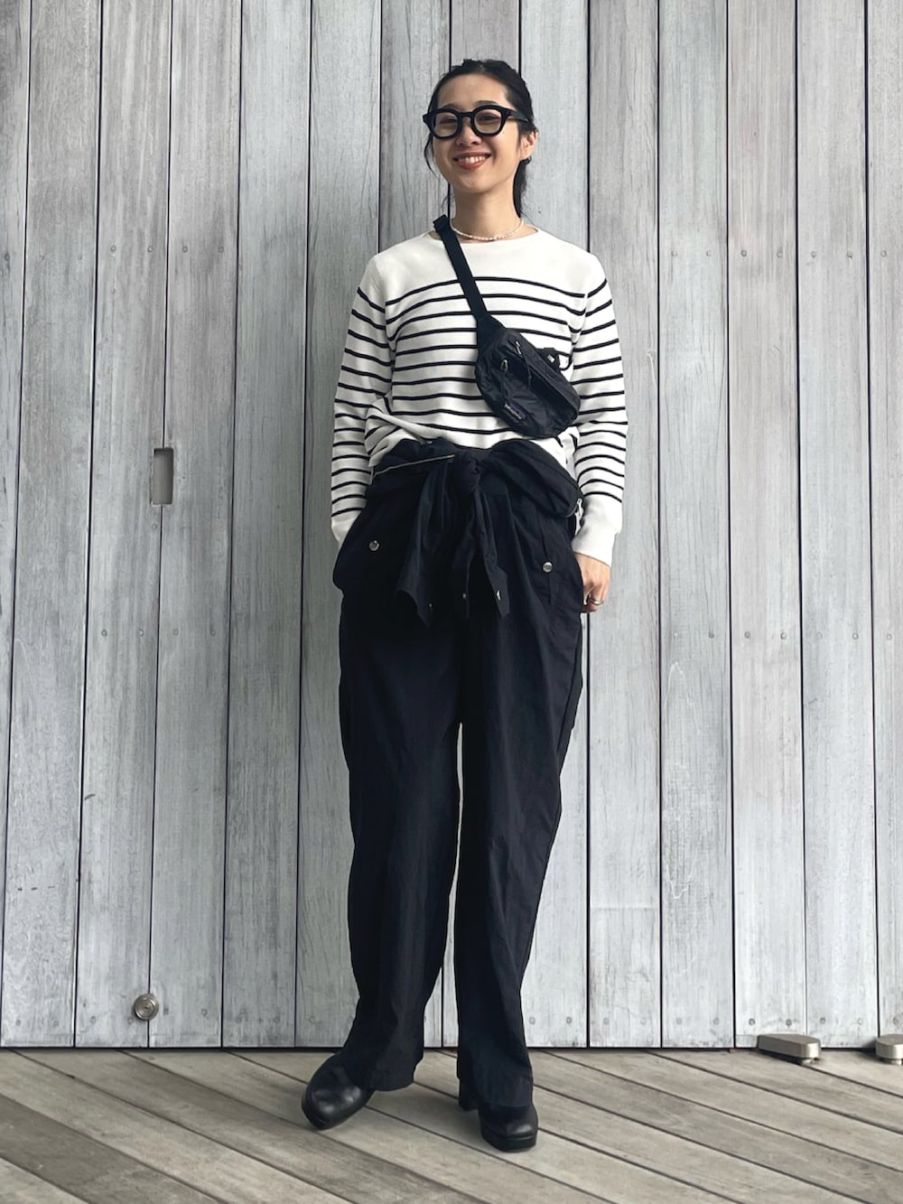 ホワイト系のニット/セーター、ブラック系のつなぎ/オールインワン、ブラック系のサンダルを着用したレディースの春コーディネートの4枚目の写真