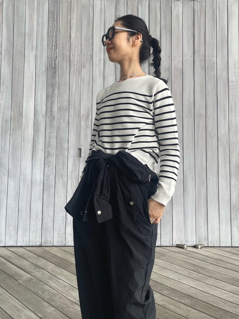 ホワイト系のニット/セーター、ブラック系のつなぎ/オールインワン、ブラック系のサンダルを着用したレディースの春コーディネートの2枚目の写真