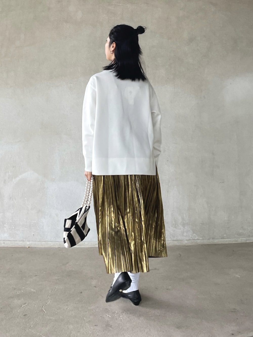 ホワイト系のスウェット、ゴールド系のスカート、ホワイト系のショルダーバッグを着用したレディースの春コーディネートの4枚目の写真