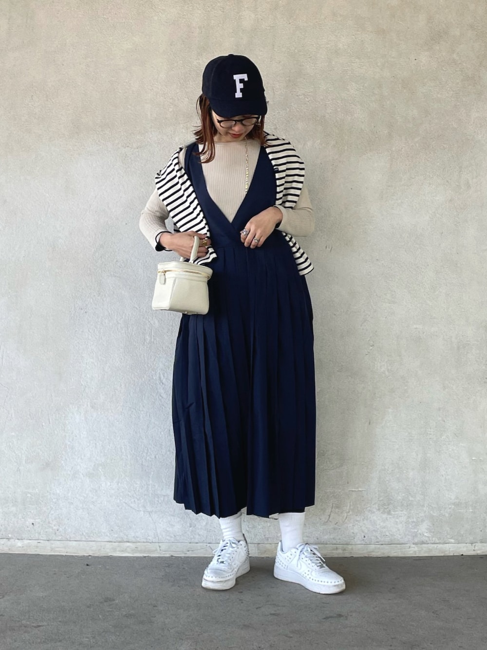 ホワイト系のTシャツ/カットソー、ベージュ系のニット/セーター、ブルー系のジャンパースカートを着用したレディースの冬コーディネートの2枚目の写真