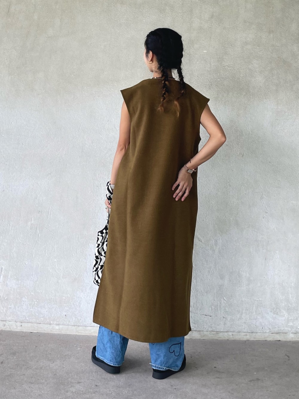 グリーン系のワンピース、ブラック系のモカシン/デッキシューズ、ブルー系のデニムパンツを着用したレディースの秋コーディネートの5枚目の写真