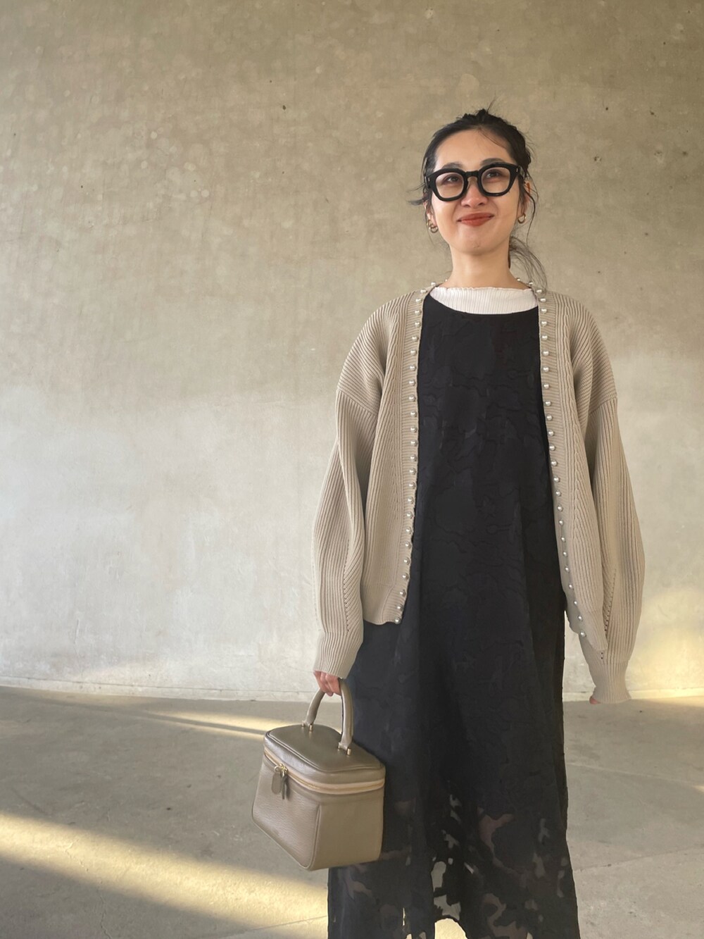 ベージュ系のカーディガン/ボレロ、ブラック系のワンピース、ブラック系のサンダルを着用したレディースの春コーディネートの4枚目の写真