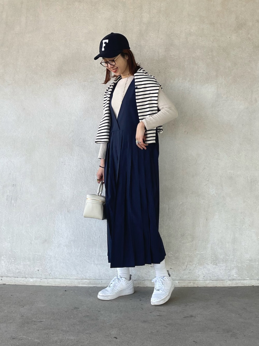 ホワイト系のTシャツ/カットソー、ベージュ系のニット/セーター、ブルー系のジャンパースカートを着用したレディースの冬コーディネートの4枚目の写真