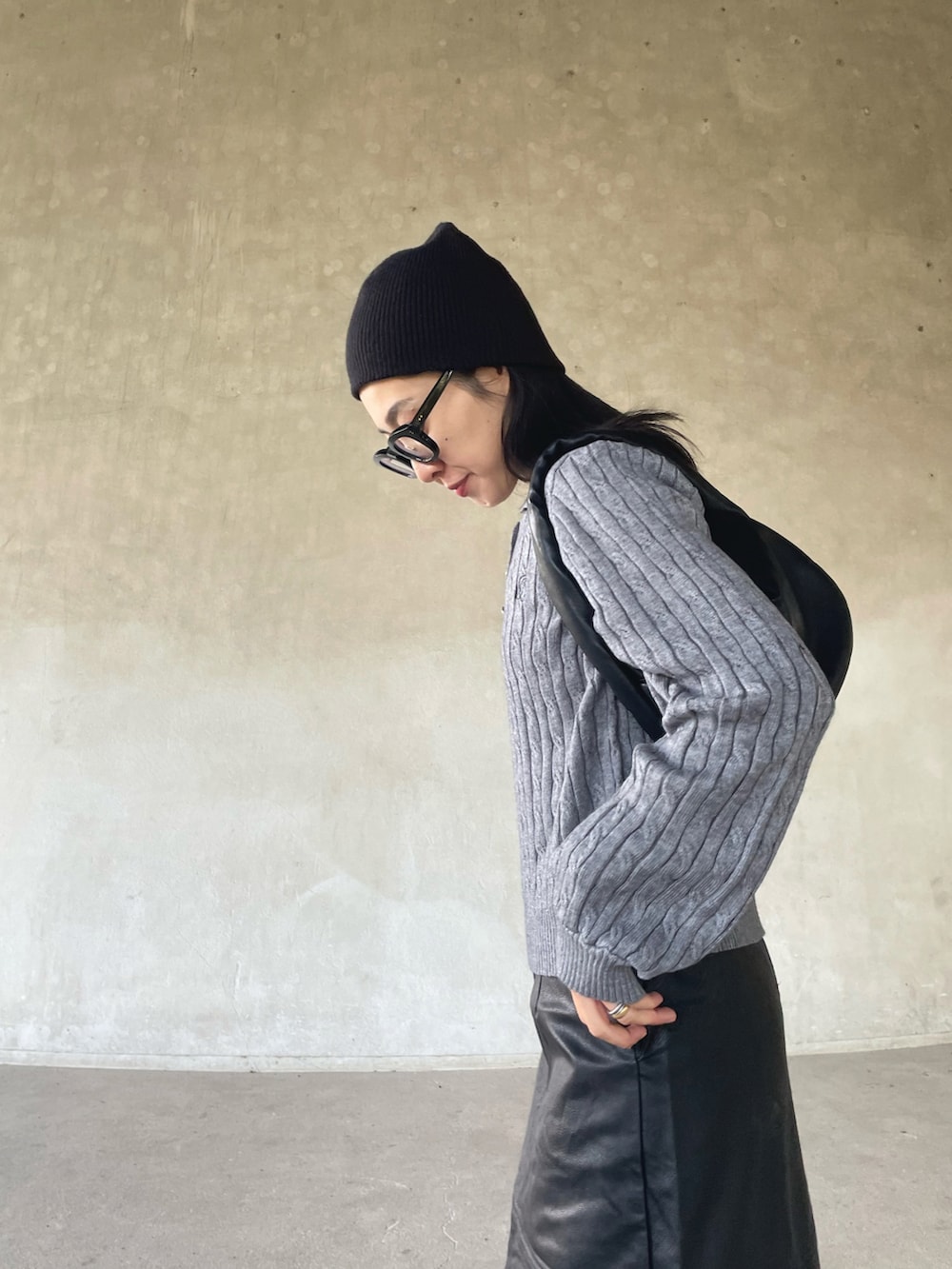 グレー系のニット/セーター、ブラック系のスカート、ホワイト系のスニーカーを着用したレディースの秋コーディネートの4枚目の写真