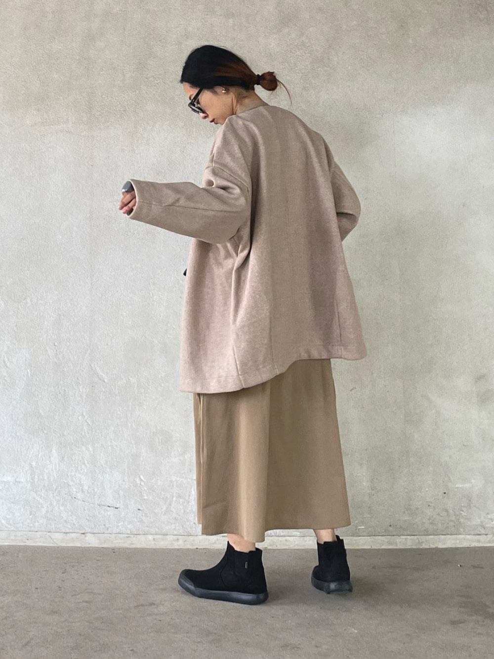 ピンク系のノーカラーコート、ベージュ系のワンピース、ブラック系のブーツを着用したレディースの秋コーディネートの2枚目の写真