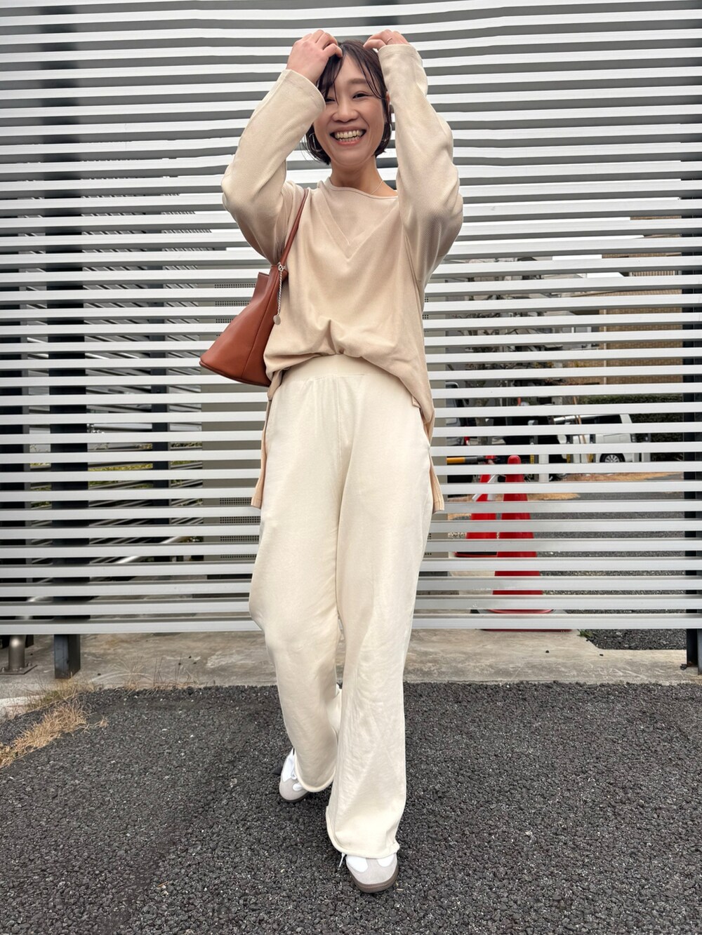 ホワイト系のスウェットパンツ、ホワイト系のスニーカー、ブラウン系のハンドバッグを着用したレディースの冬コーディネートの4枚目の写真