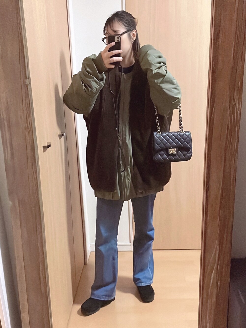 グリーン系のブルゾン、ブルー系のスウェット、ブルー系のデニムパンツを着用したレディースの秋コーディネートの2枚目の写真