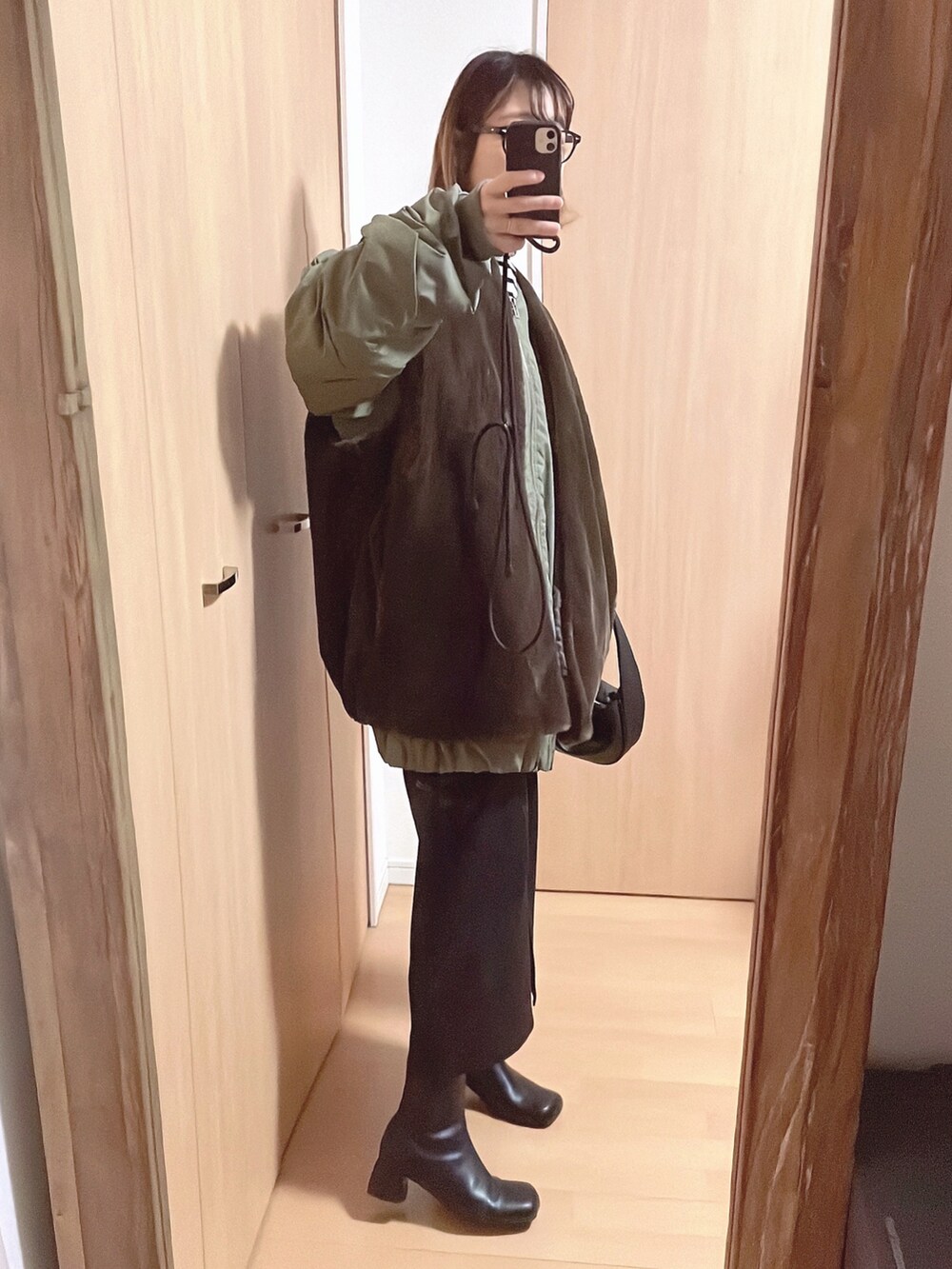 グリーン系のブルゾン、ホワイト系のニット/セーター、ブラック系のスカートを着用したレディースの秋コーディネートの2枚目の写真