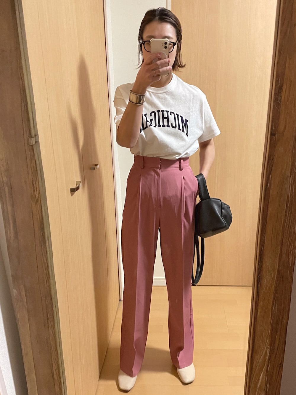 ホワイト系のブルゾン、ピンク系のスラックス、ブラック系のショルダーバッグを着用したレディースの春コーディネートの2枚目の写真