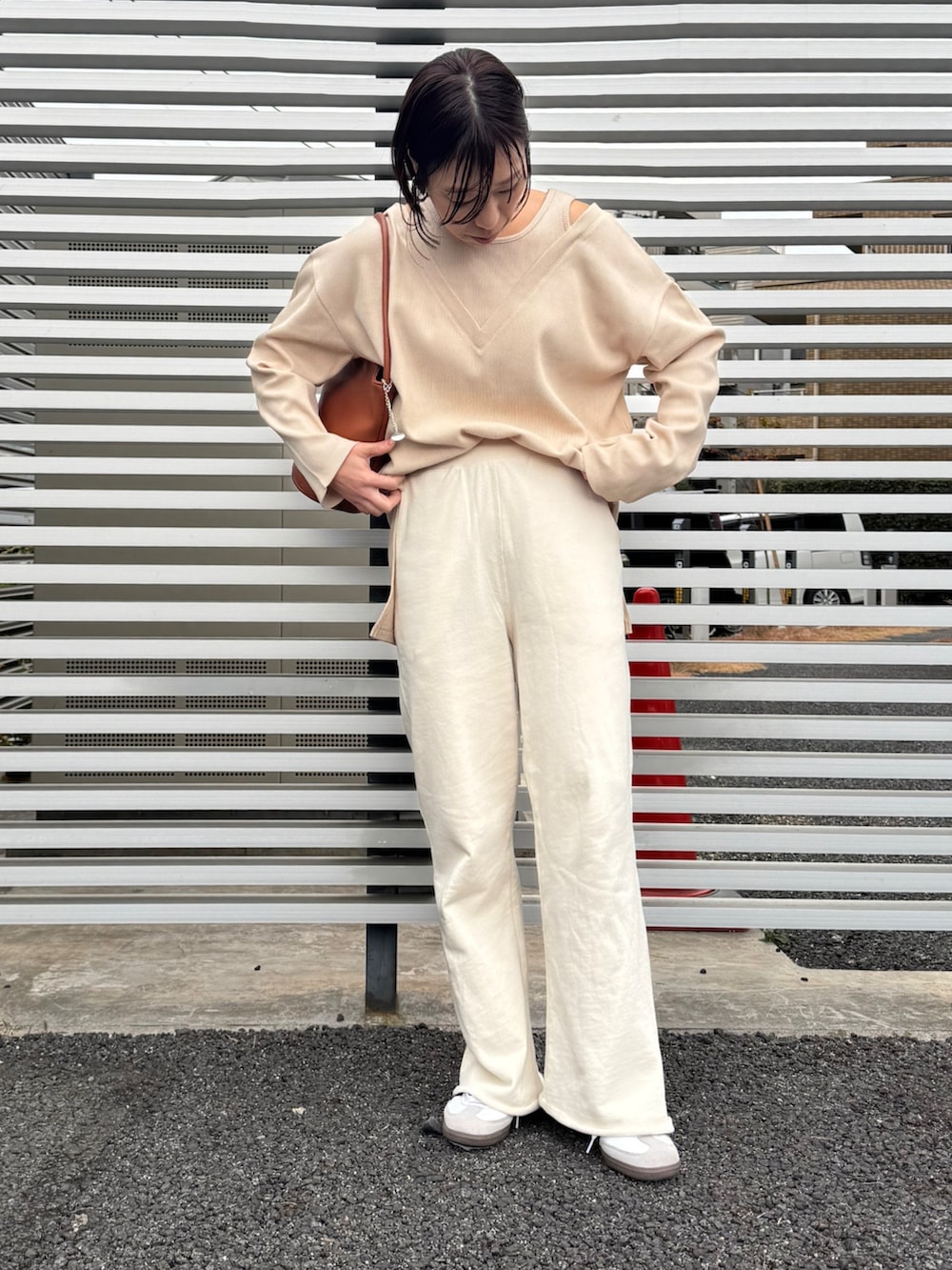 ホワイト系のスウェットパンツ、ホワイト系のスニーカー、ブラウン系のハンドバッグを着用したレディースの冬コーディネートの3枚目の写真