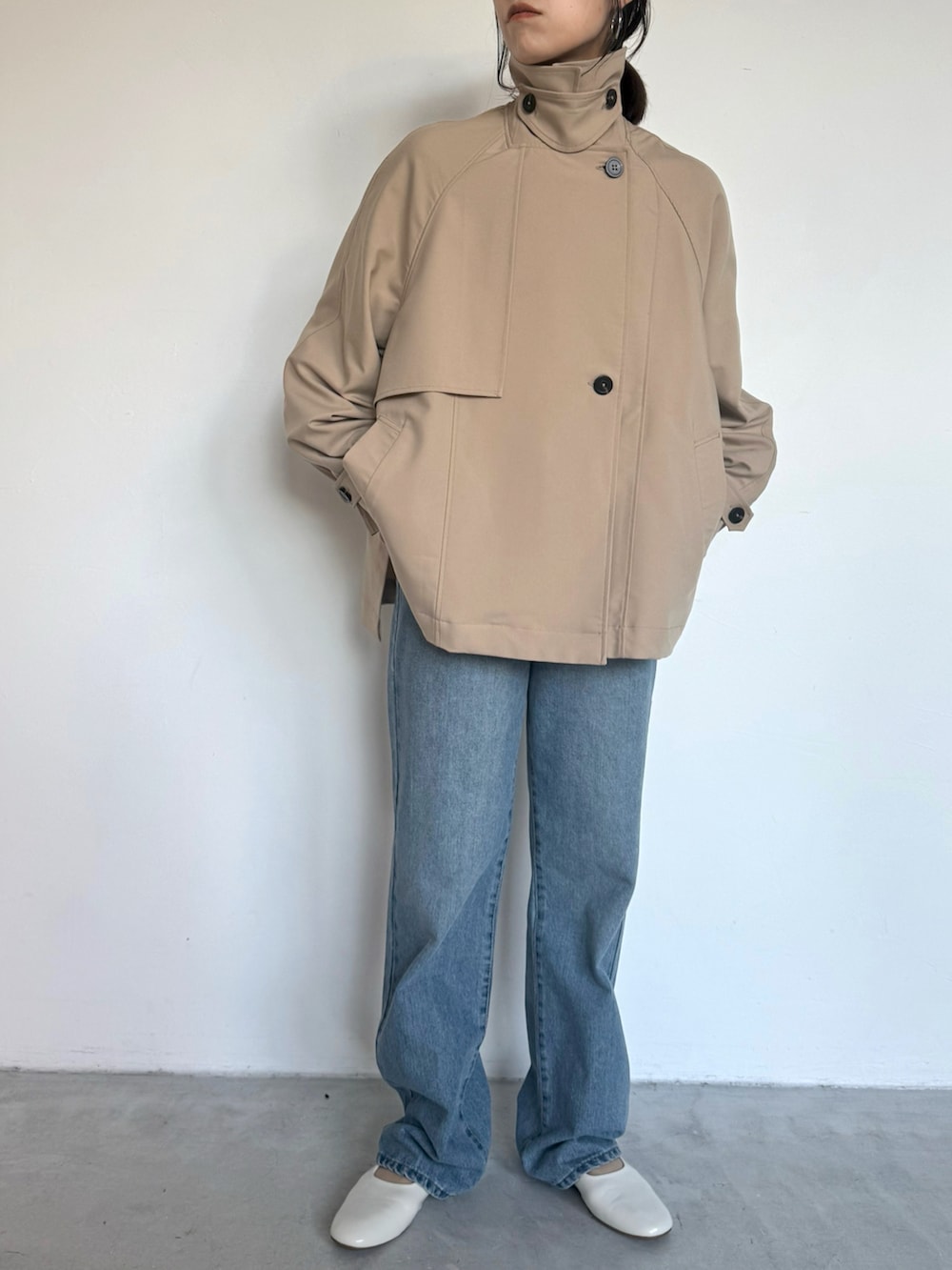 ブルー系のデニムパンツ、ベージュ系のトレンチコート、ブルー系のスウェットを着用したレディースの冬コーディネートの2枚目の写真