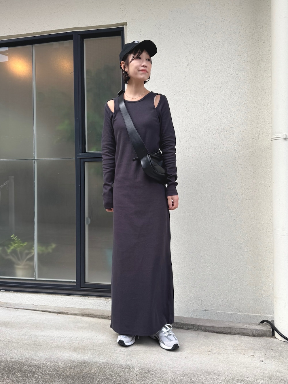 ブラック系のショルダーバッグ、グレー系のスニーカー、ブラック系のワンピースを着用したレディースの冬コーディネートの2枚目の写真