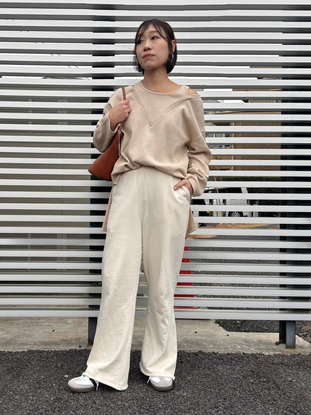 ホワイト系のスウェットパンツ、ホワイト系のスニーカー、ブラウン系のハンドバッグを着用したレディースの冬コーディネートの2枚目の写真