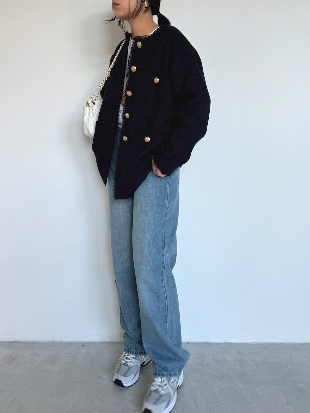 ブルー系のデニムパンツ、グレー系のスニーカー、ブルー系のノーカラージャケットを着用したレディースの冬コーディネートの2枚目の写真