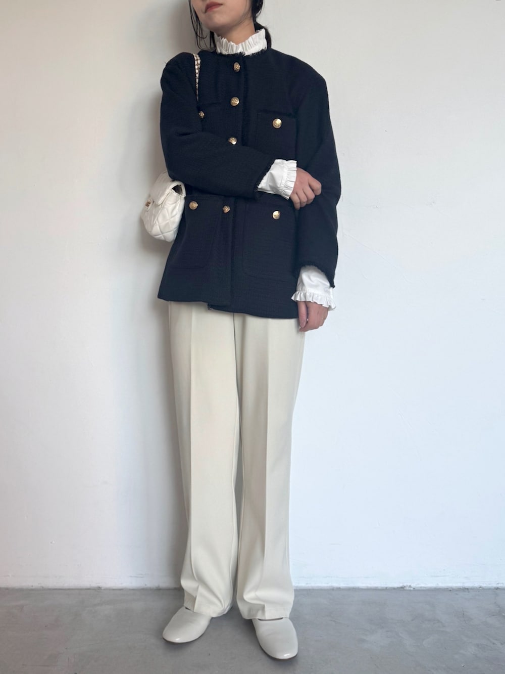 ホワイト系のスラックス、ホワイト系のシャツ/ブラウス、ブラック系のショルダーバッグを着用したレディースの冬コーディネートの2枚目の写真