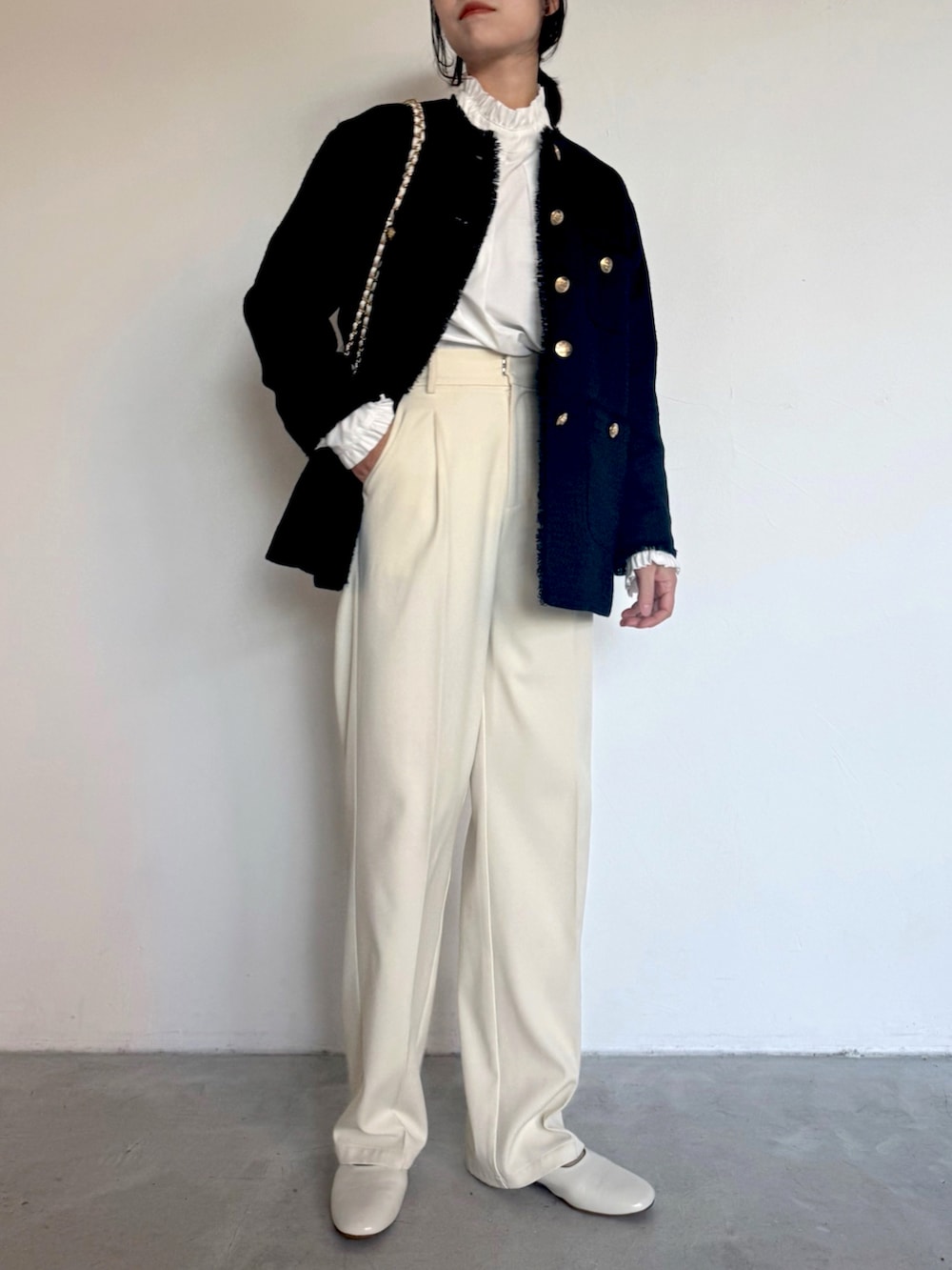 ホワイト系のスラックス、ホワイト系のシャツ/ブラウス、ブラック系のショルダーバッグを着用したレディースの冬コーディネートの3枚目の写真