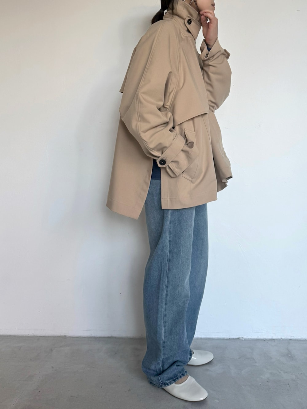 ブルー系のデニムパンツ、ベージュ系のトレンチコート、ブルー系のスウェットを着用したレディースの冬コーディネートの3枚目の写真