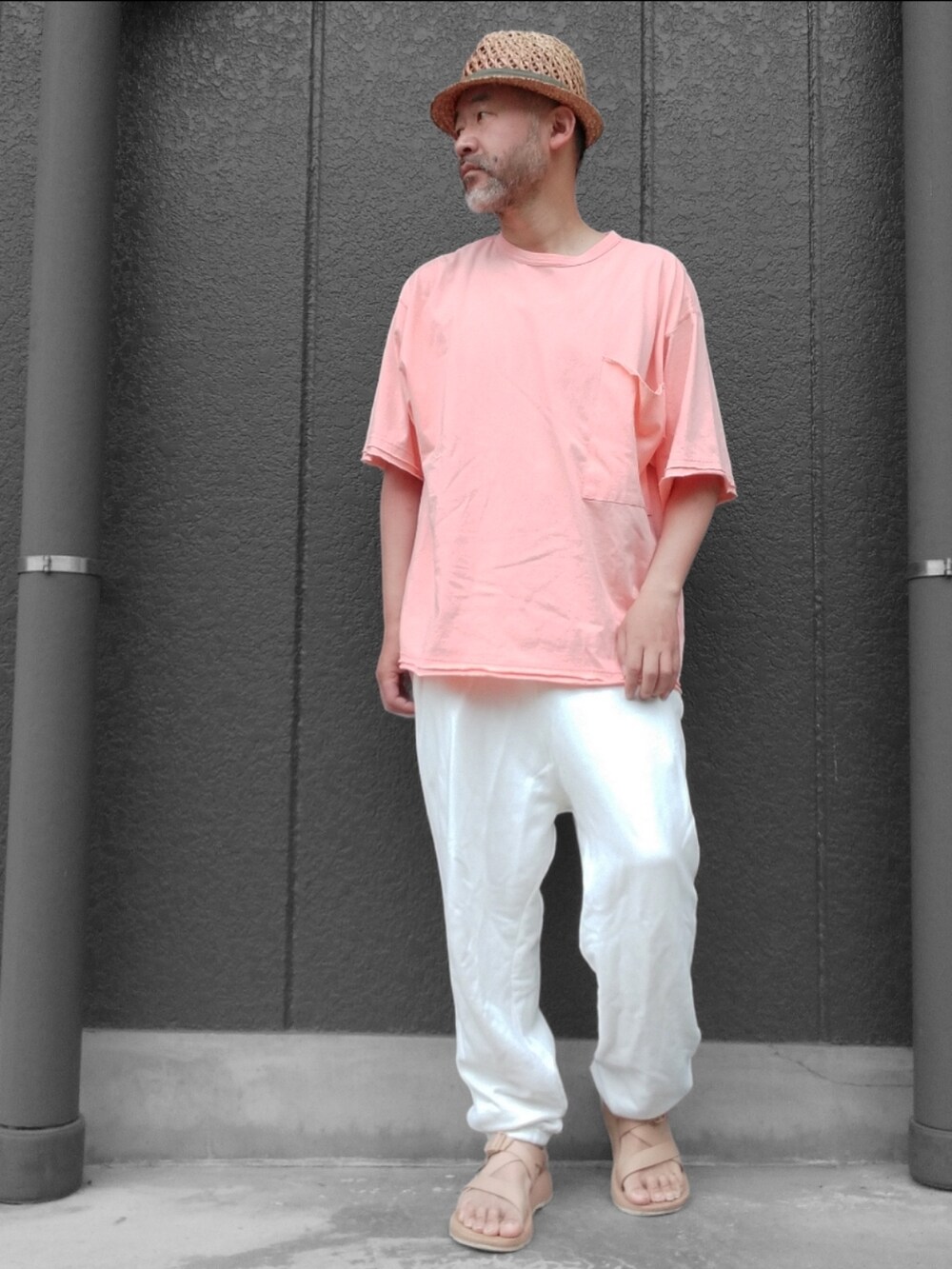 ホワイト系のスウェットパンツ、ベージュ系のサンダル、オレンジ系のTシャツ/カットソーを着用したメンズの夏コーディネートの2枚目の写真