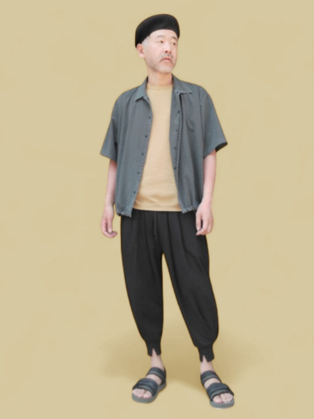 グレー系のパンツ、グリーン系のサンダル、イエロー系のニット/セーターを着用したメンズの春コーディネートの2枚目の写真