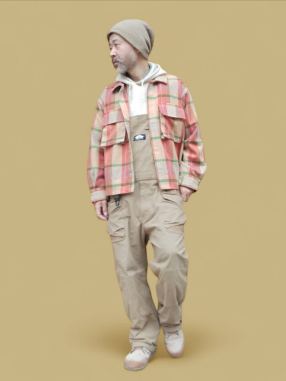 ベージュ系のサロペット/オーバーオール、ベージュ系のスニーカー、ベージュ系のパーカーを着用したメンズの秋コーディネートの3枚目の写真