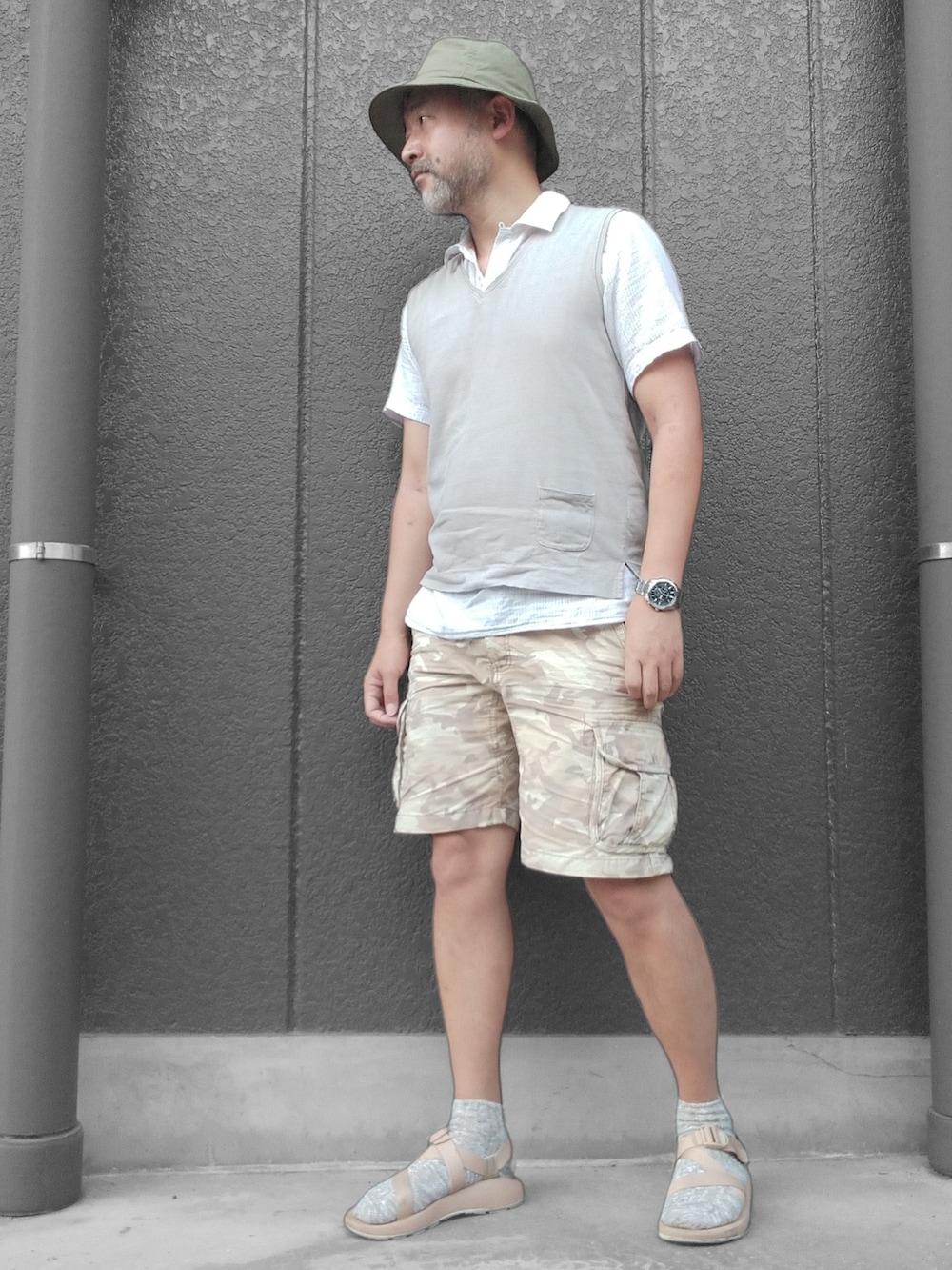 グレー系のベスト、ベージュ系のカーゴパンツ、ベージュ系のサンダルを着用したメンズの夏コーディネートの4枚目の写真