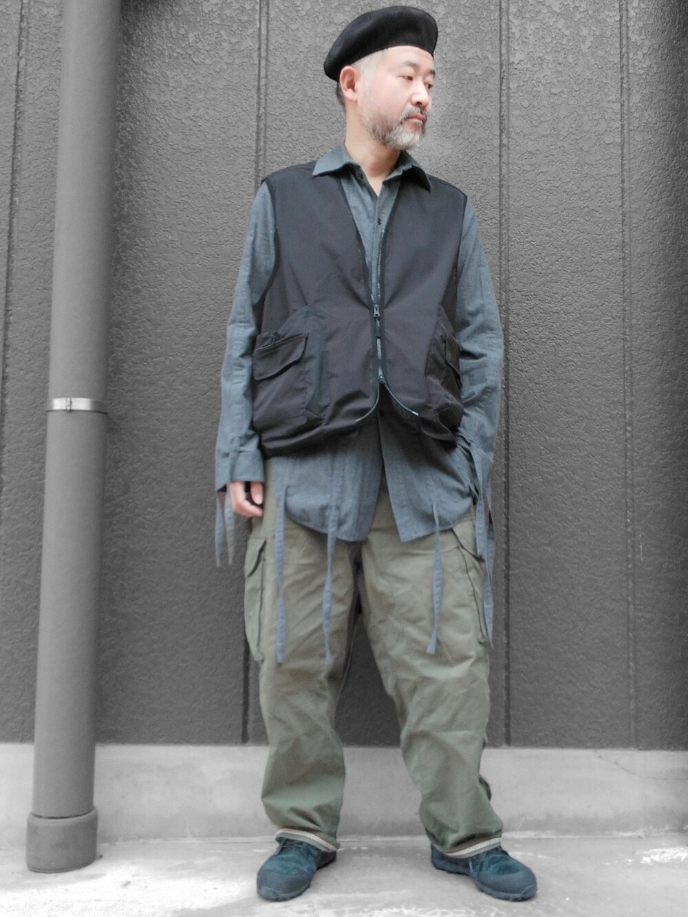 グリーン系のカーゴパンツ、ブラック系のスニーカー、ブラック系のベストを着用したメンズの冬コーディネートの4枚目の写真