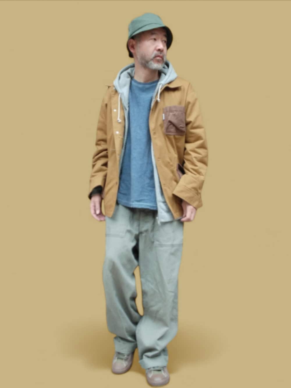 グリーン系のカーゴパンツ、グリーン系のスニーカー、イエロー系のカバーオールを着用したメンズの冬コーディネートの2枚目の写真