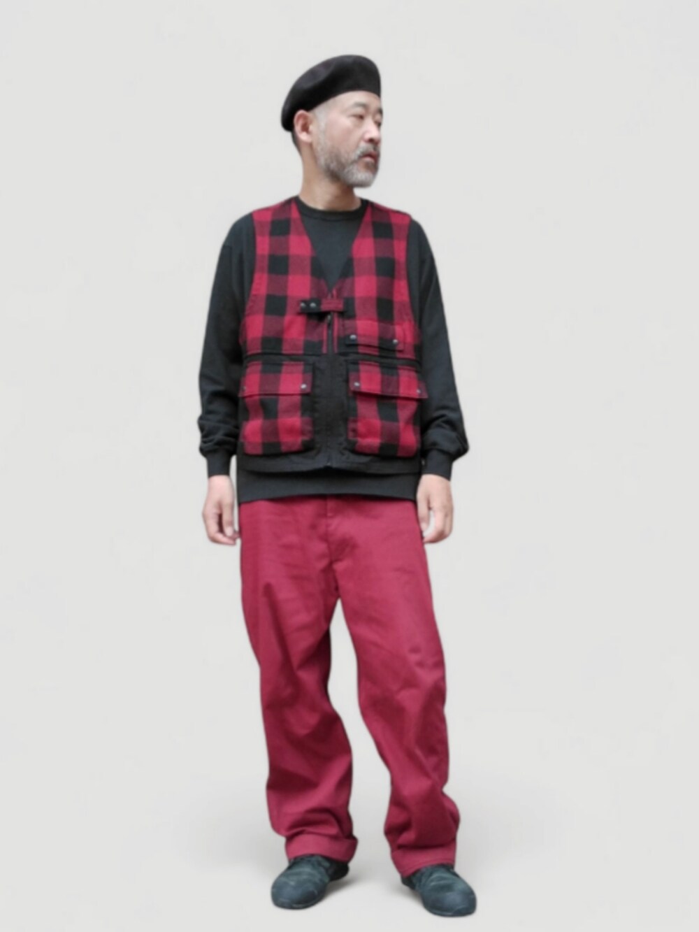 レッド系のチノパンツ、レッド系のベスト、ブラック系のスニーカーを着用したメンズの秋コーディネートの4枚目の写真