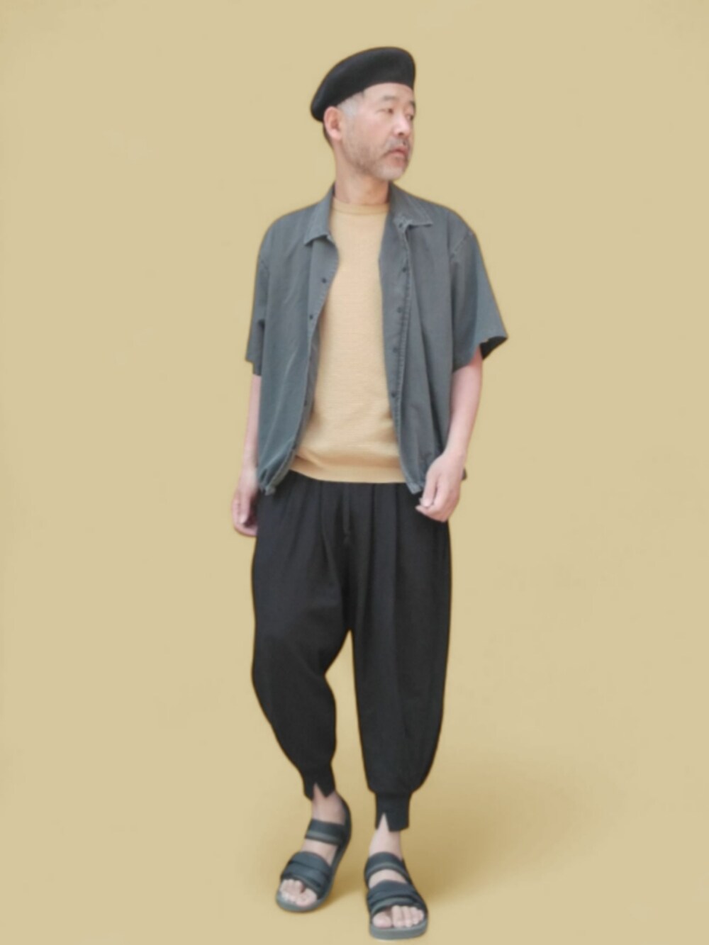 グレー系のパンツ、グリーン系のサンダル、イエロー系のニット/セーターを着用したメンズの春コーディネートの3枚目の写真