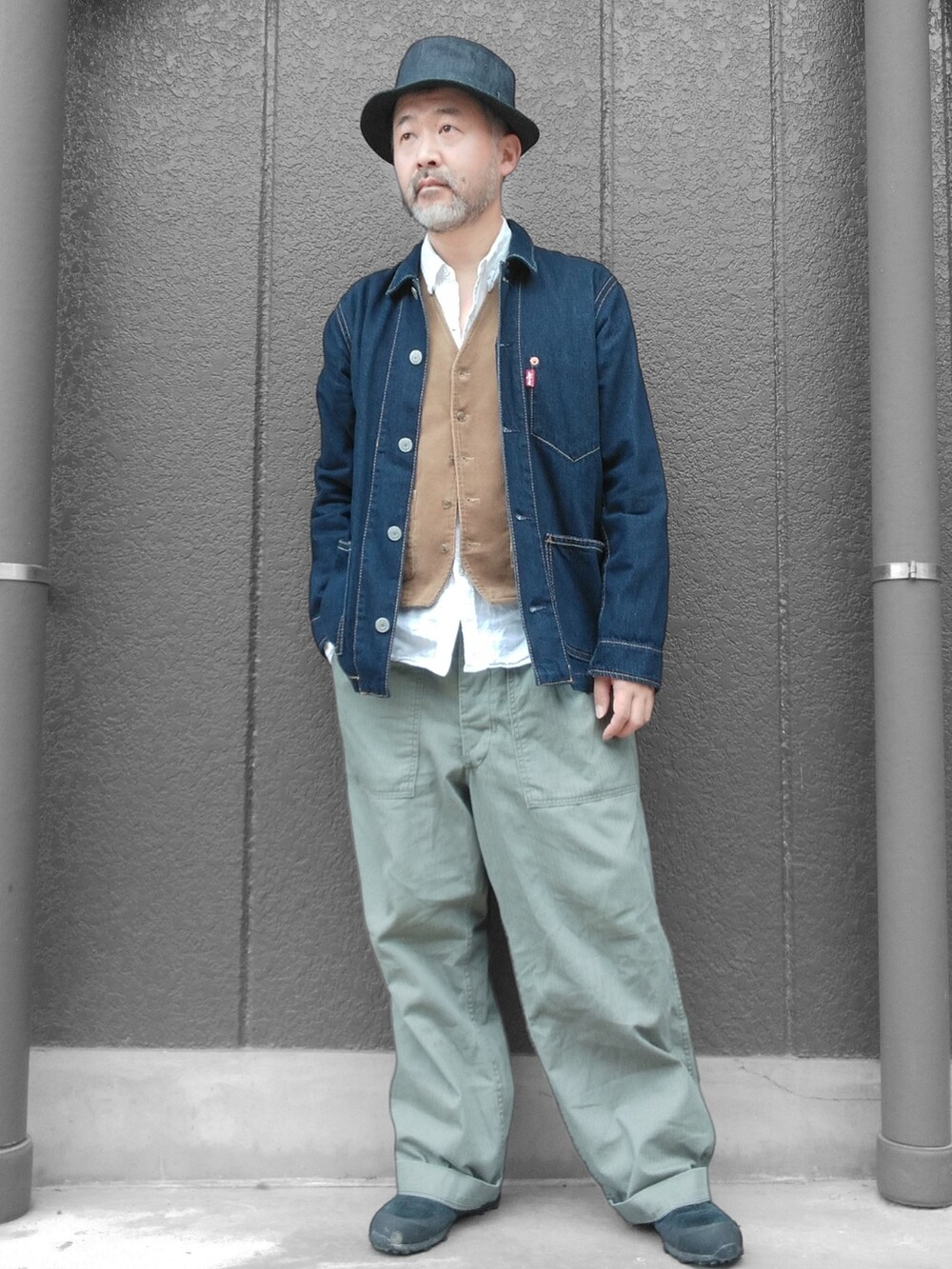 グリーン系のカーゴパンツ、ブルー系のデニムジャケット、ベージュ系のベストを着用したメンズの秋コーディネートの4枚目の写真
