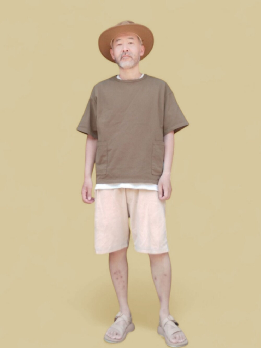 グリーン系のTシャツ/カットソー、イエロー系のパンツ、ベージュ系のサンダルを着用したメンズの夏コーディネートの2枚目の写真