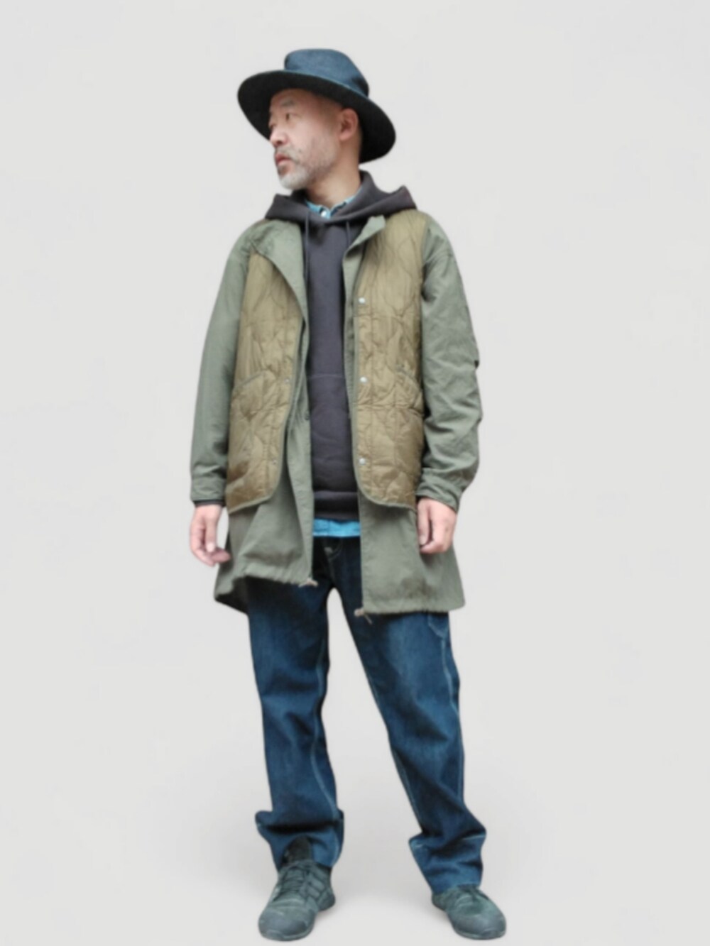 ブラック系のパーカー、グリーン系のベスト、ブルー系のデニムパンツを着用したメンズの秋コーディネートの3枚目の写真