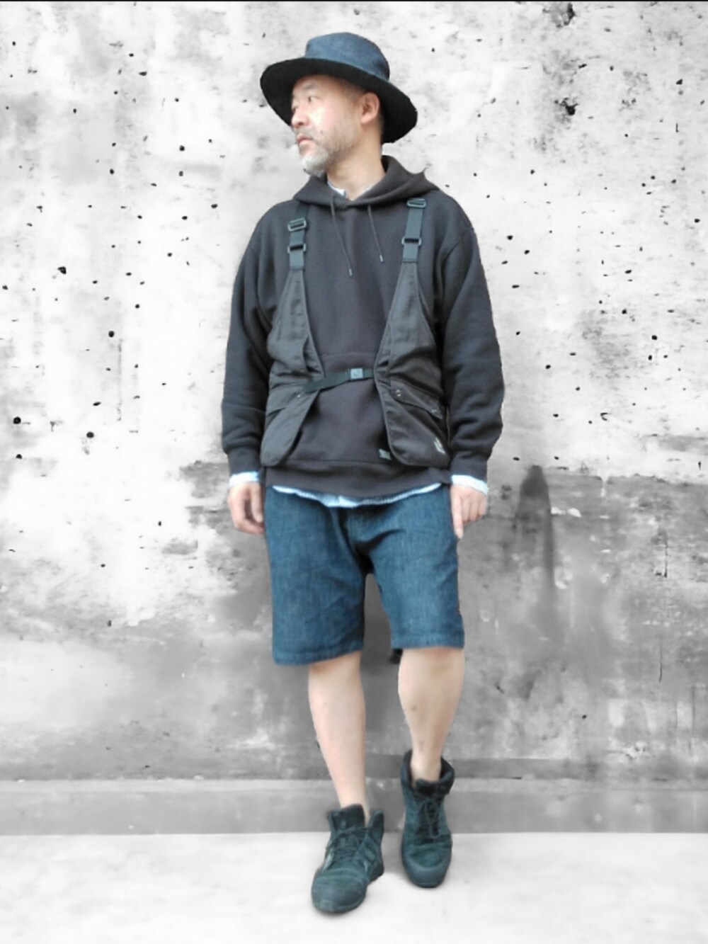 ブラック系のベスト、ブルー系のデニムパンツ、ブラック系のスニーカーを着用したメンズの春コーディネートの2枚目の写真