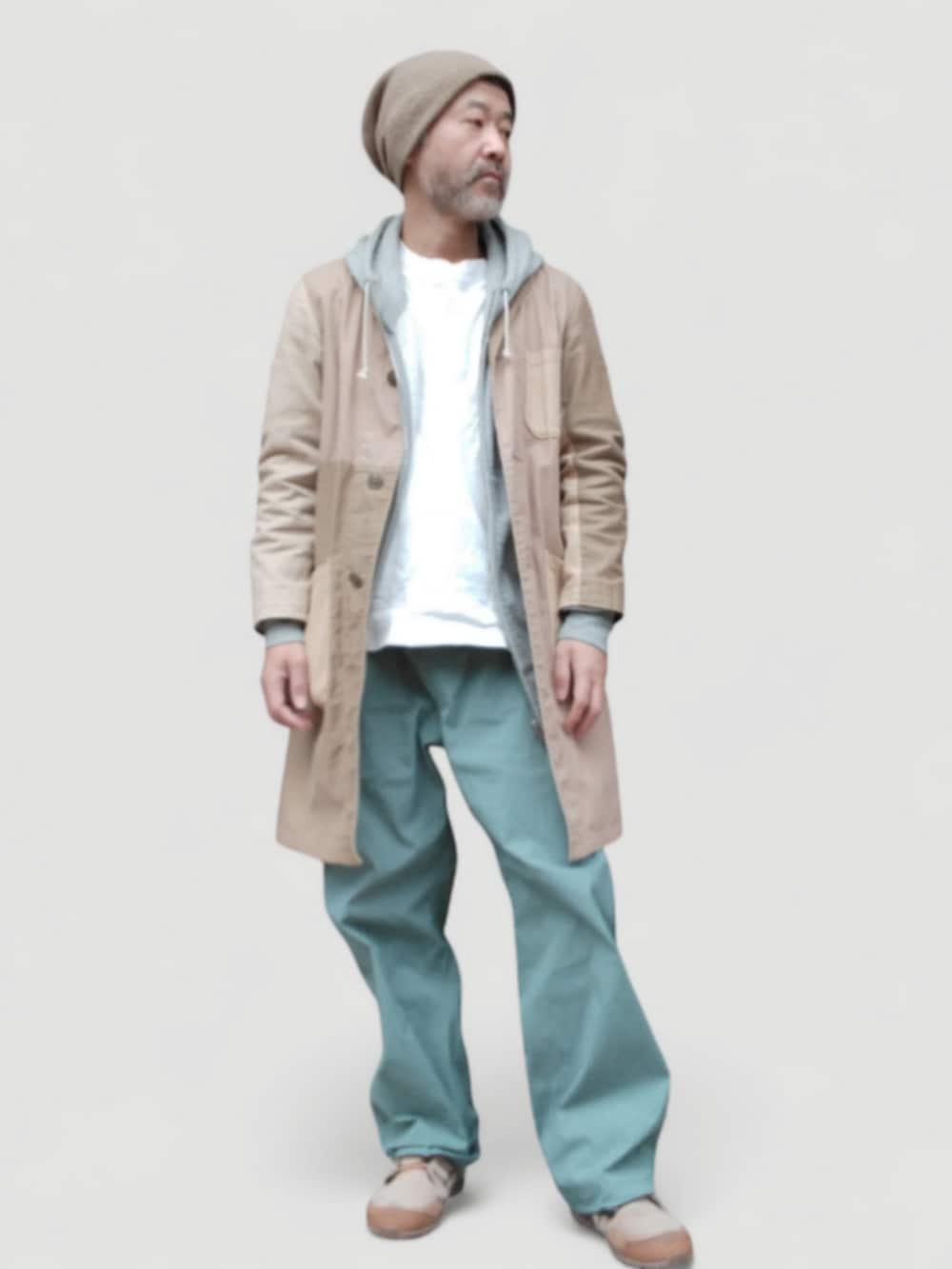 グリーン系のパンツ、ベージュ系のスニーカー、ベージュ系のステンカラーコートを着用したメンズの冬コーディネートの4枚目の写真