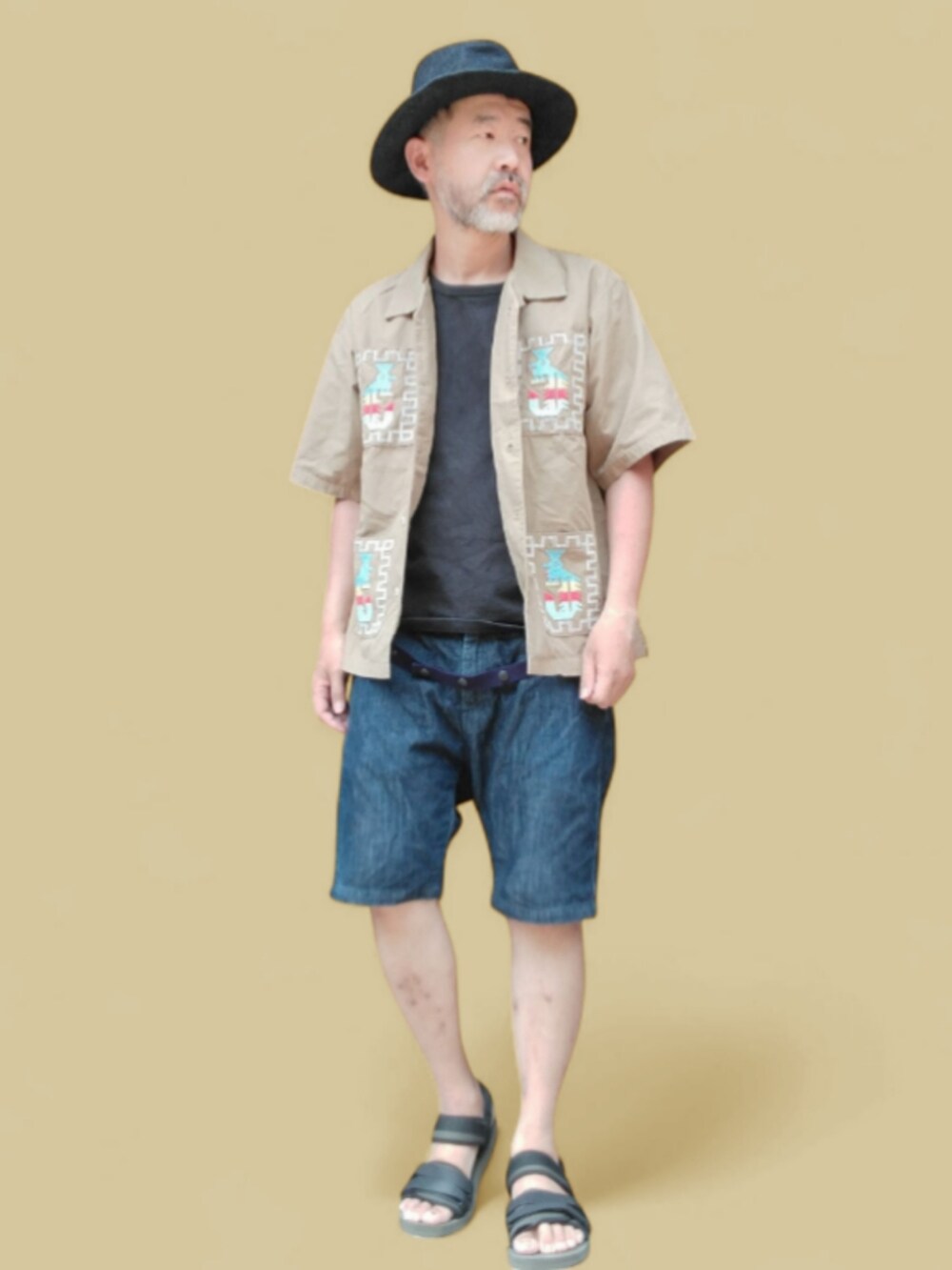 ブルー系のデニムパンツ、ブラック系のサンダル、ベージュ系のシャツ/ブラウスを着用したメンズの夏コーディネートの3枚目の写真
