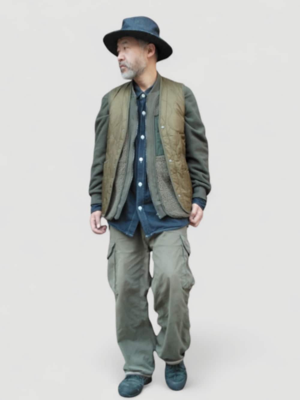 グリーン系のカーゴパンツ、グリーン系のベスト、ブルー系のハットを着用したメンズの冬コーディネートの2枚目の写真