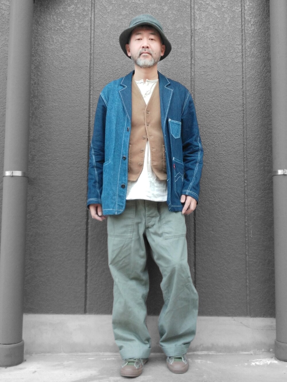 グリーン系のカーゴパンツ、ブルー系のデニムジャケット、ベージュ系のベストを着用したメンズの冬コーディネートの3枚目の写真