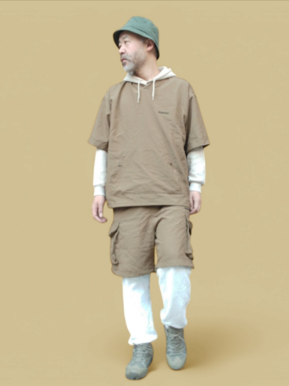 ホワイト系のスウェットパンツ、ベージュ系のパーカー、グリーン系のスニーカーを着用したメンズの冬コーディネートの2枚目の写真