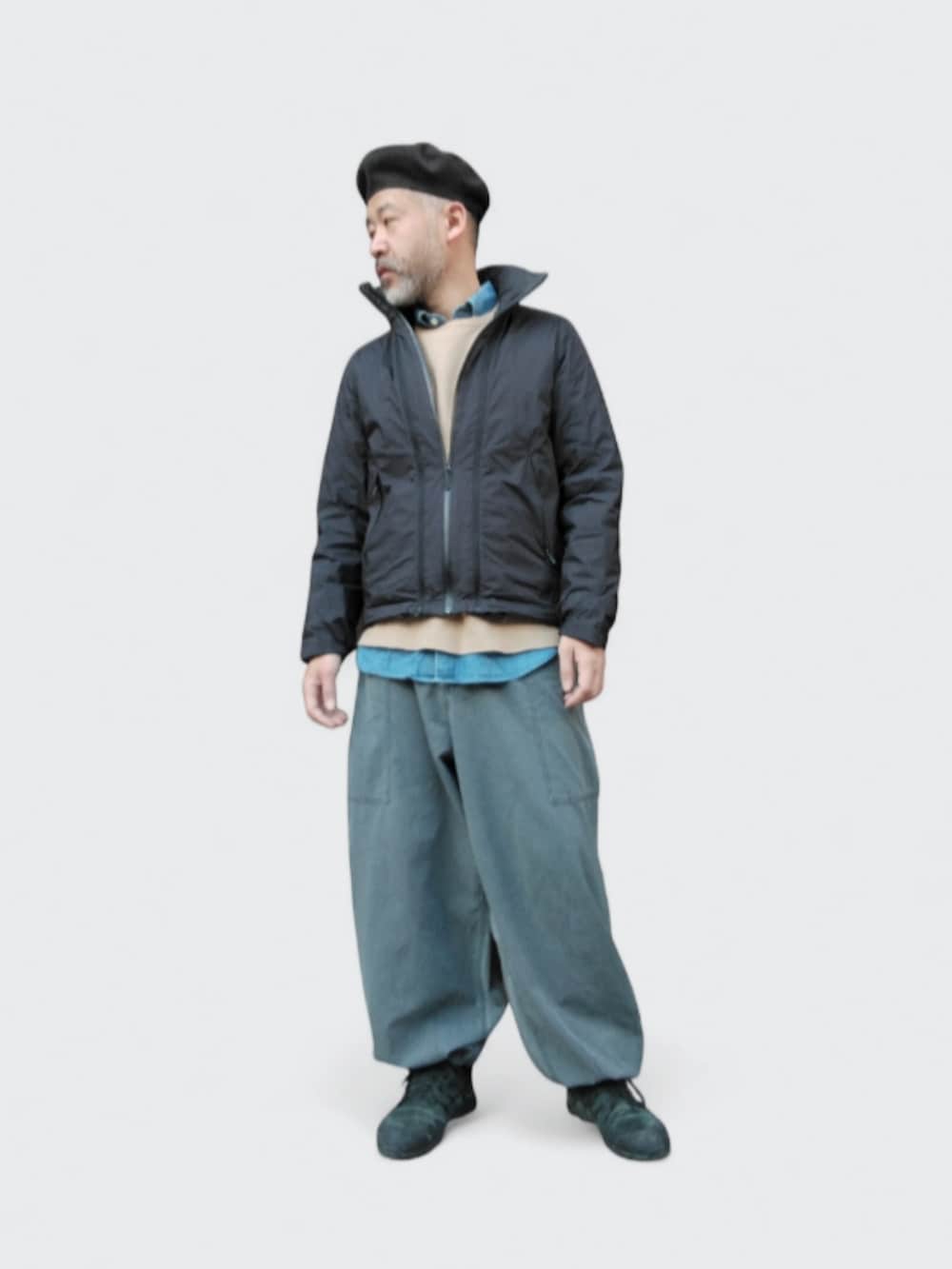 グレー系のパンツ、ブラック系のダウンジャケット/コート、ブラック系のスニーカーを着用したメンズの冬コーディネートの2枚目の写真