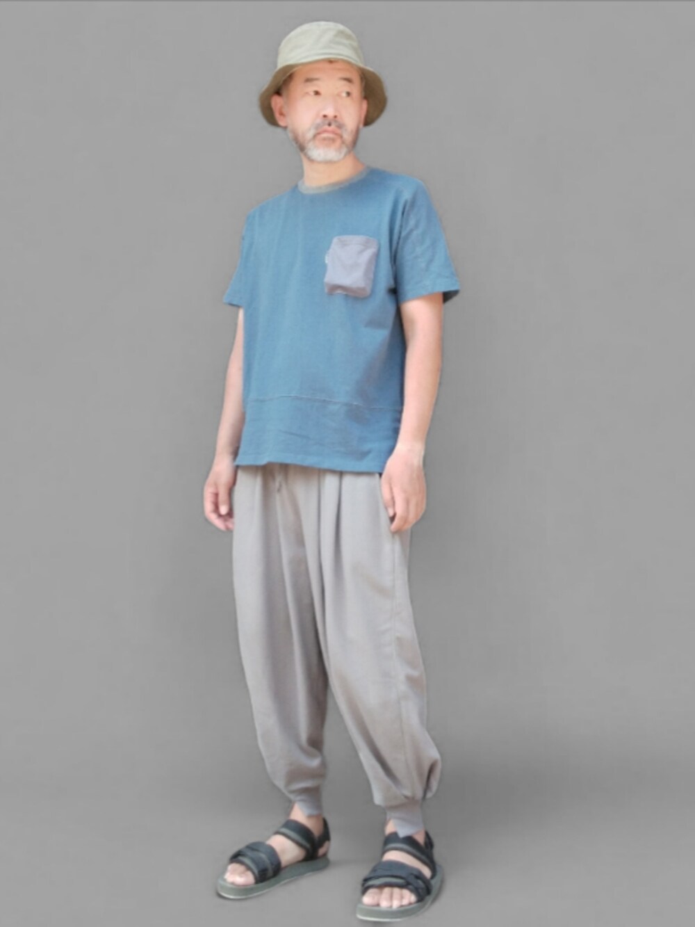 グレー系のスウェットパンツ、グリーン系のサンダル、ブルー系のTシャツ/カットソーを着用したメンズの夏コーディネートの4枚目の写真