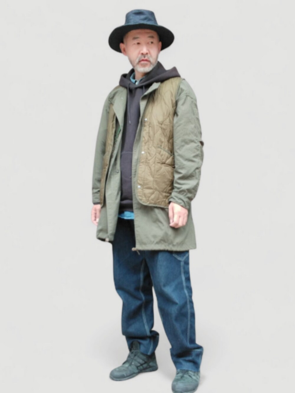 ブラック系のパーカー、グリーン系のベスト、ブルー系のデニムパンツを着用したメンズの秋コーディネートの2枚目の写真