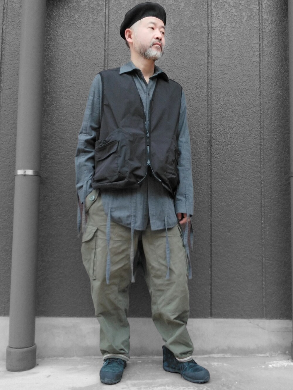 グリーン系のカーゴパンツ、ブラック系のスニーカー、ブラック系のベストを着用したメンズの冬コーディネートの2枚目の写真