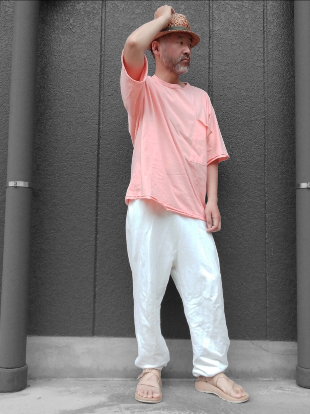 ホワイト系のスウェットパンツ、ベージュ系のサンダル、オレンジ系のTシャツ/カットソーを着用したメンズの夏コーディネートの3枚目の写真