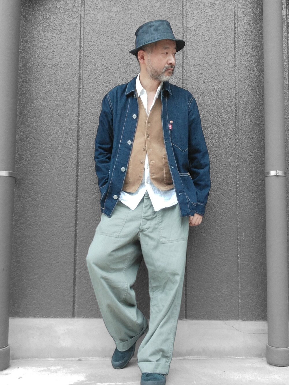 グリーン系のカーゴパンツ、ブルー系のデニムジャケット、ベージュ系のベストを着用したメンズの秋コーディネートの3枚目の写真