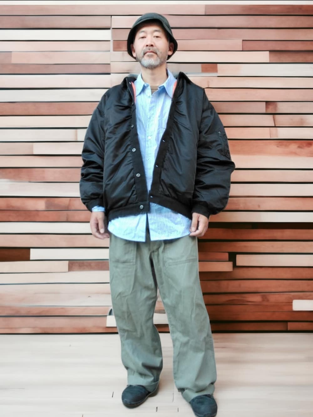 グリーン系のカーゴパンツ、ブラック系のスニーカー、ブラック系のブルゾンを着用したメンズの秋コーディネートの3枚目の写真