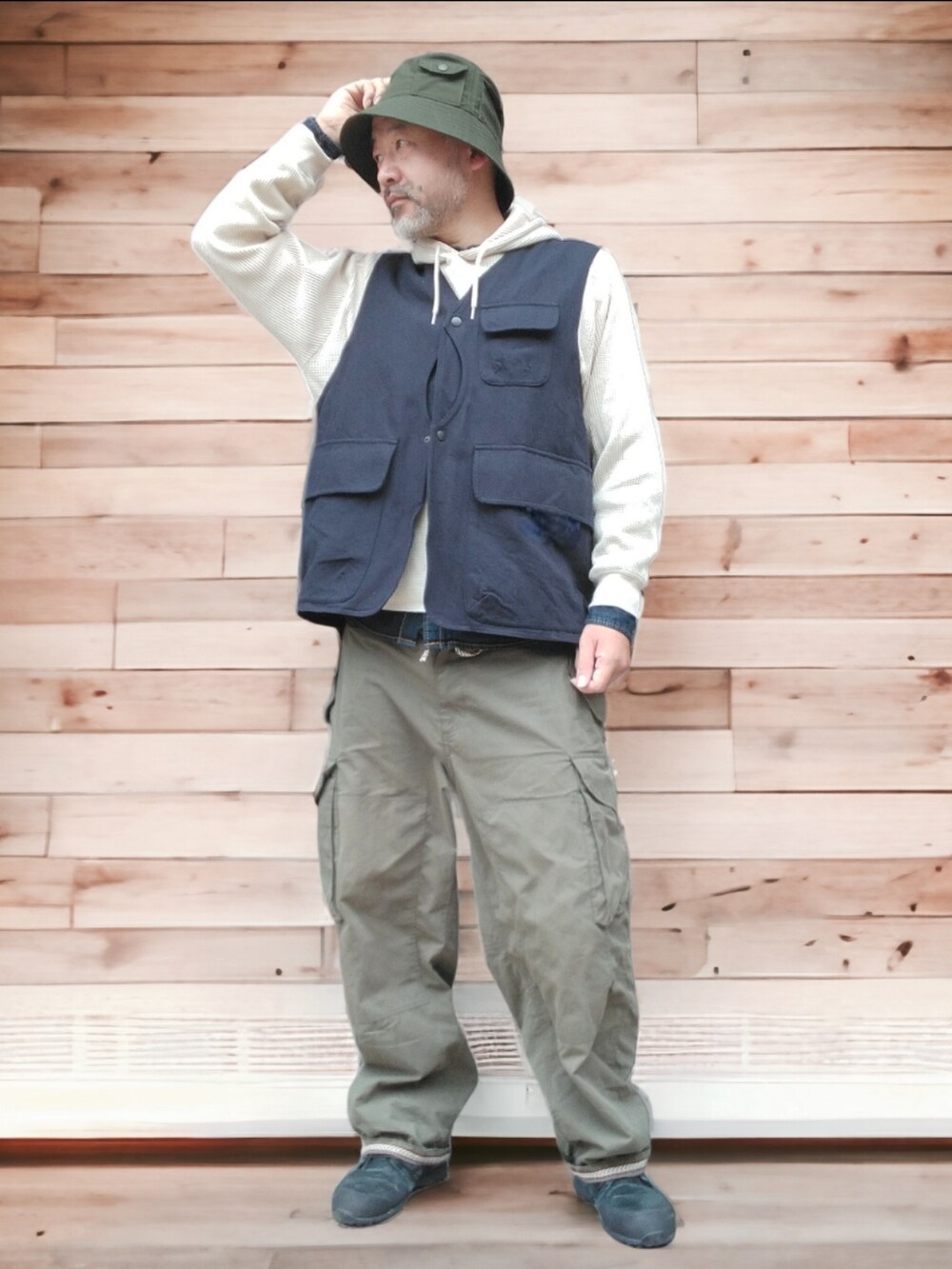 グリーン系のカーゴパンツ、ブラック系のスニーカー、ブルー系のベストを着用したメンズの秋コーディネートの2枚目の写真