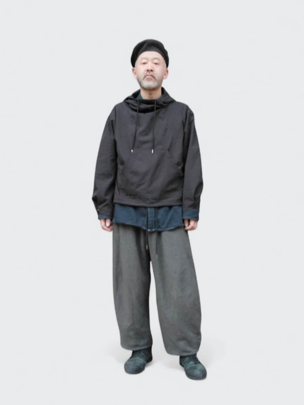 グレー系のパンツ、ブラック系のパーカー、ブラック系のハンチング/ベレー帽を着用したメンズの冬コーディネートの3枚目の写真