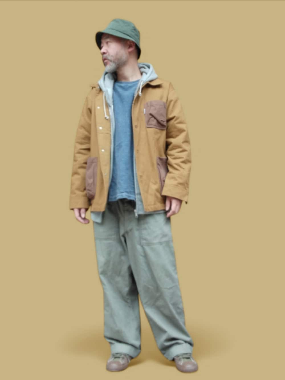 グリーン系のカーゴパンツ、グリーン系のスニーカー、イエロー系のカバーオールを着用したメンズの冬コーディネートの3枚目の写真