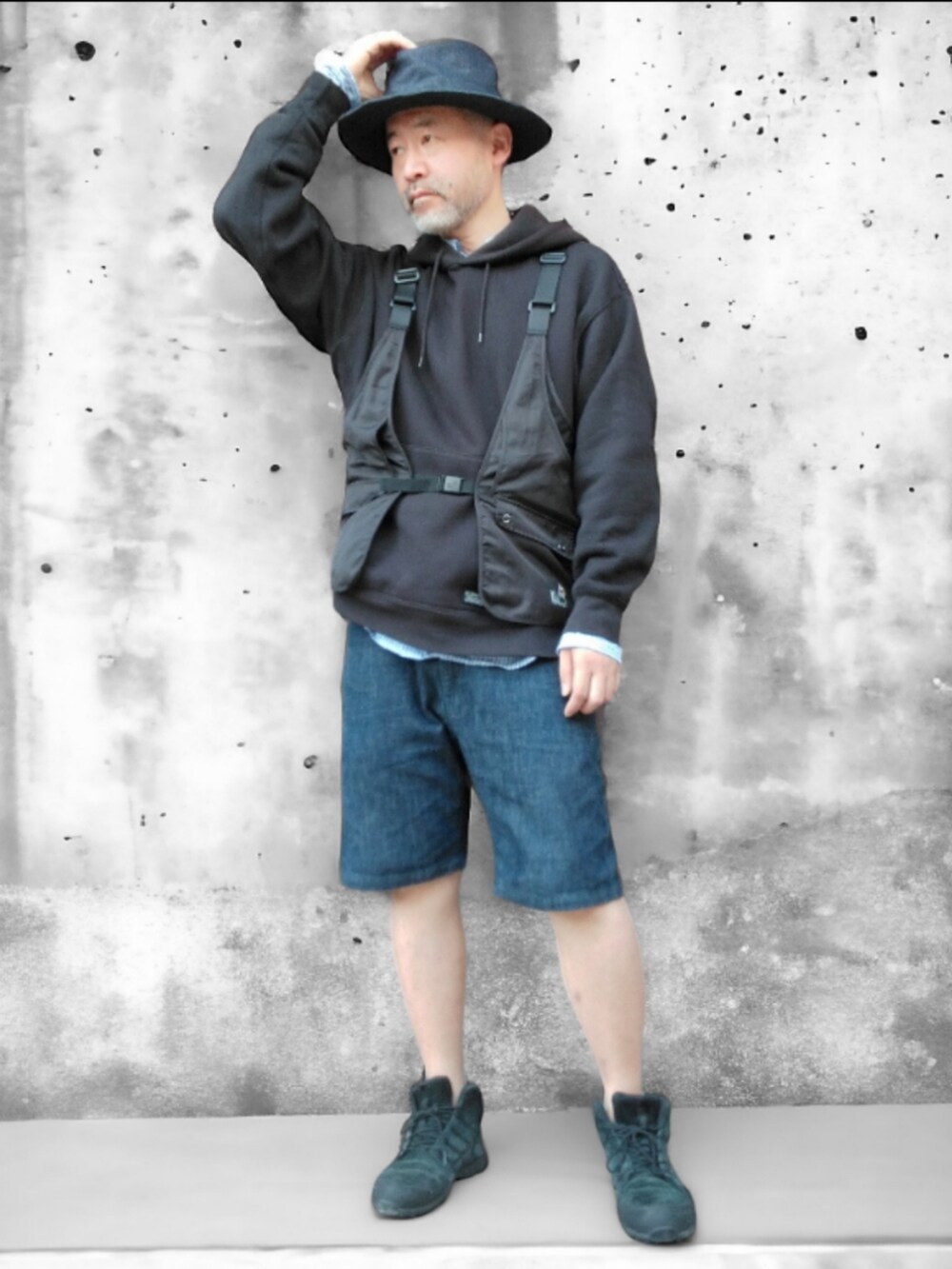 ブラック系のベスト、ブルー系のデニムパンツ、ブラック系のスニーカーを着用したメンズの春コーディネートの4枚目の写真