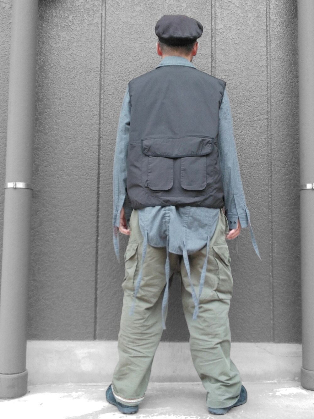 グリーン系のカーゴパンツ、ブラック系のスニーカー、ブラック系のベストを着用したメンズの冬コーディネートの5枚目の写真